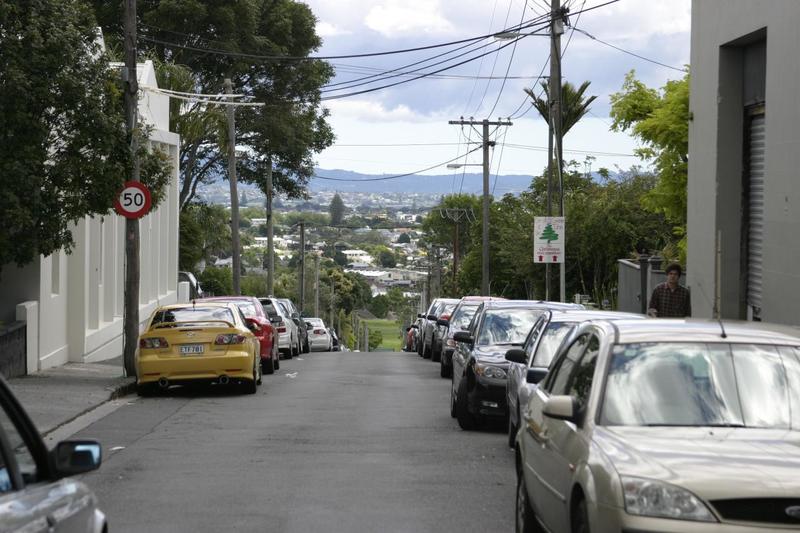 A residential street in Auckland full of parked cars.